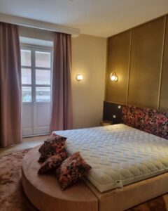 Letto matrimoniale con materasso bianco, cuscini floreali e parete dorata.