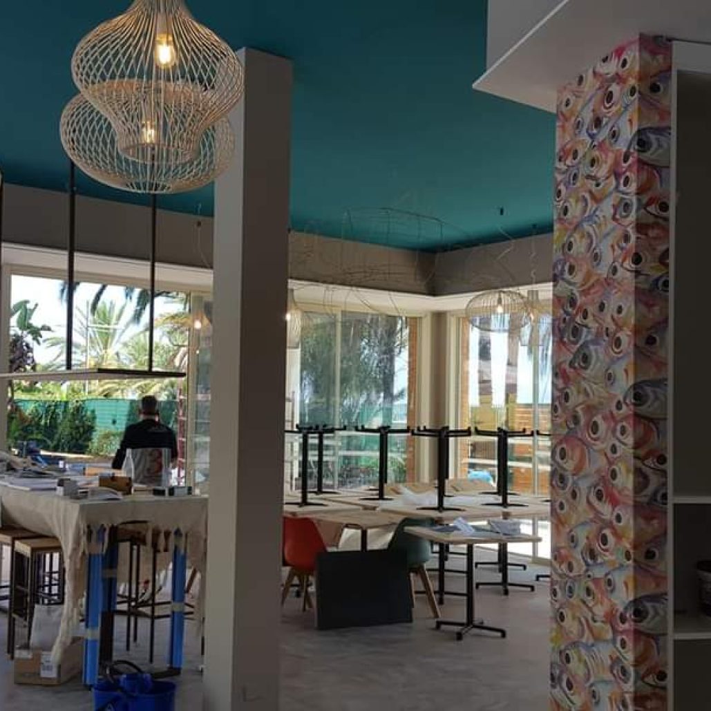 Interno di ristorante con lampadari moderni e decorazioni murali vivaci.