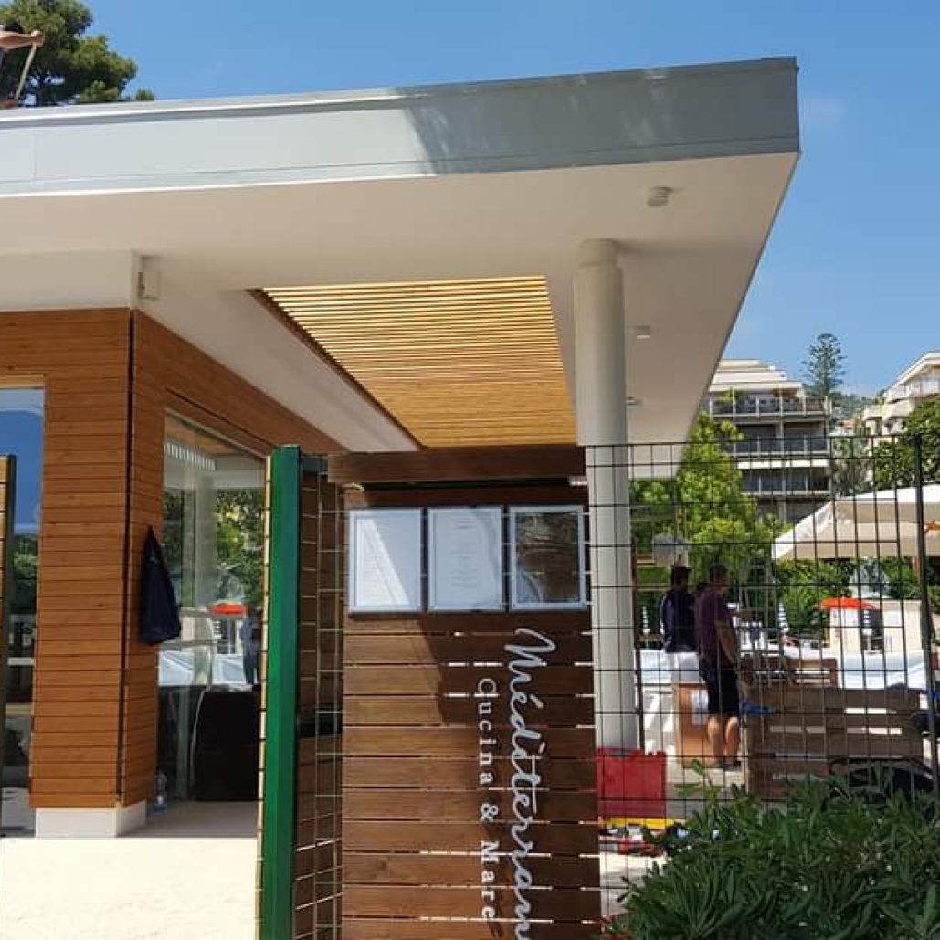 Ingresso moderno del ristorante con rivestimenti in legno e pergolato.