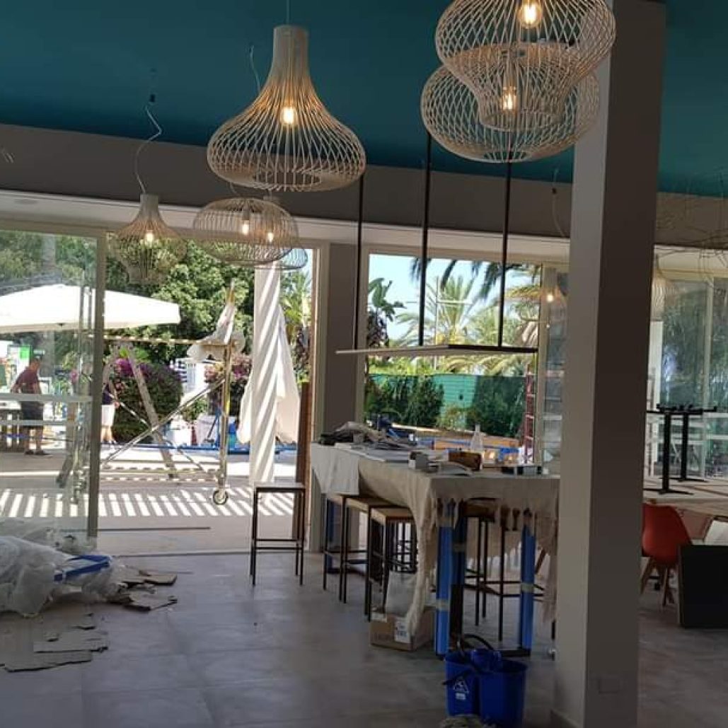 Interno di un locale in ristrutturazione con lampadari moderni e vetrate luminose.
