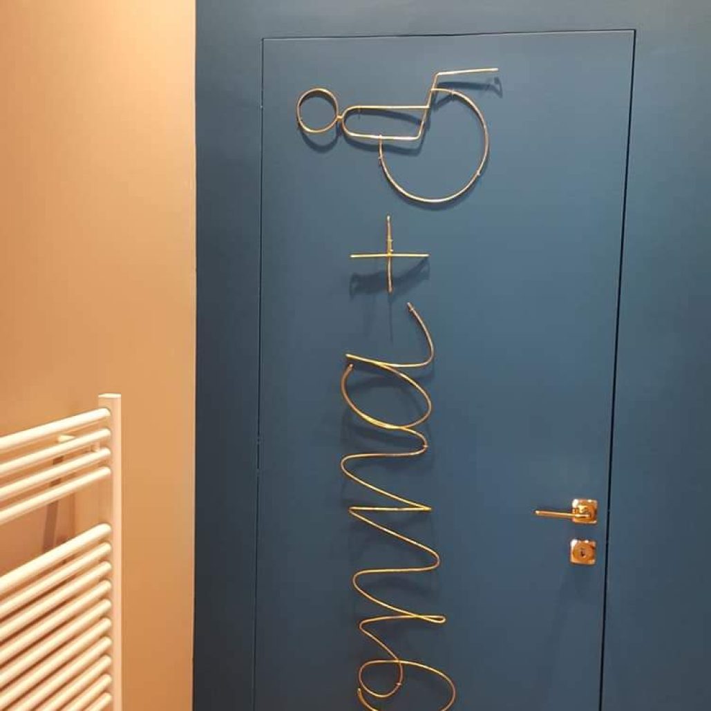 Porta moderna con scritta decorativa in metallo e pareti dai colori eleganti.