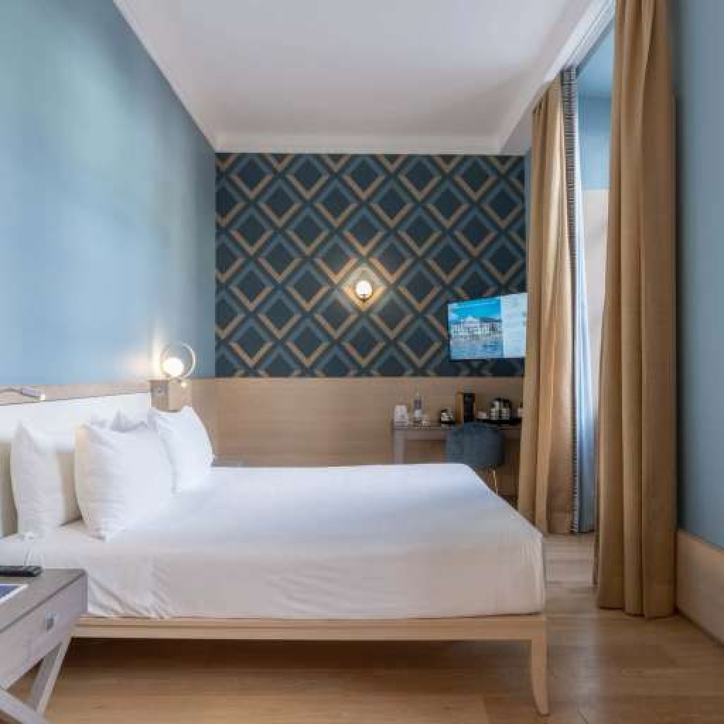 Letto matrimoniale moderno con struttura blu e decorazioni tropicali.